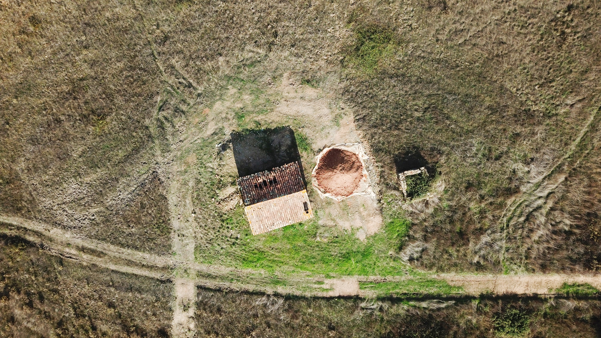 Aerial view of a stone ruin, brick yard and earth pit within the surrounding landscape