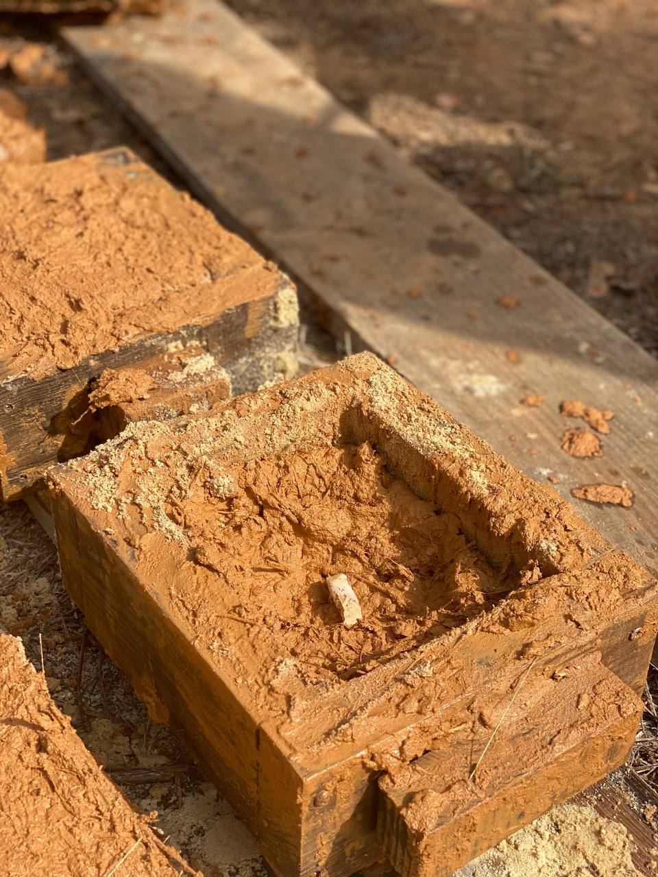 Adobe brick curing inside a wooden mould