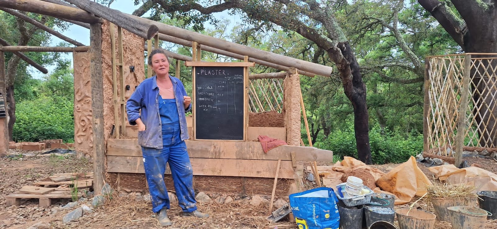 Griet teaching beside a chalkboard comparing clay and lime plasters